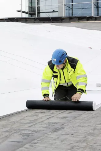 Valkoista Metallic-katetta asennetaan Oodi-kirjaston katolle. Bitumikattorullan levittäminen katolle
