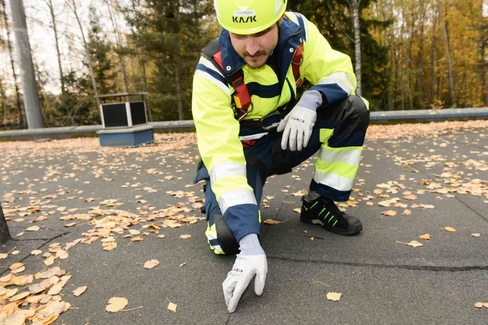 Icopal katto oyn kattotarkastaja katsoo ja kokeilee bitumikaton saumaa kattovuodon varalta